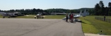 Image shows planes on the tarmac at the Stanhope Municipal Airport with a group of people talking. 